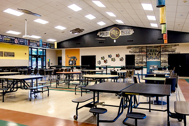 Modern school cafeteria with mobile folding cafeteria tables and attached round stools arranged for flexible student seating.